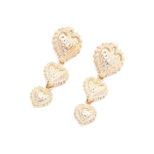 Close-up of golden triple-layered heart earrings with hammered texture and vintage finish