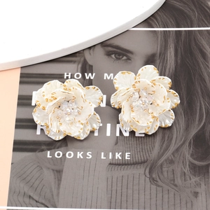 Elegant white floral stud earrings with gold edges and sparkling crystals on fashion magazine