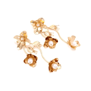 Details von goldenen Blumenohrringen mit Schichtblättern und feinen Perlenakzenten