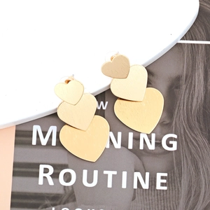 Three-tier layered heart drop earrings with golden brushed metal texture and minimalist design