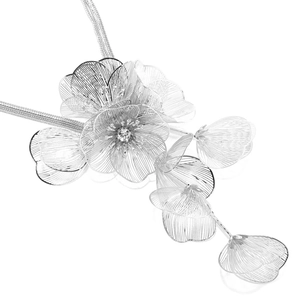 Macro detail of silver floral pendant with layered hollow petals and a crystal center
