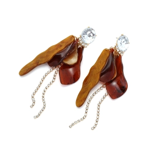Macro detail of long leaf tassel earrings with amber resin petals and rhinestone chains
