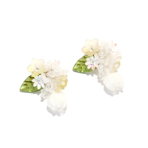 Détail de boucles d'oreilles muguet faites main avec feuilles vertes et pétales jaunes
