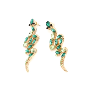 Detail of gold snake earrings featuring vibrant green pear-shaped crystal embellishments