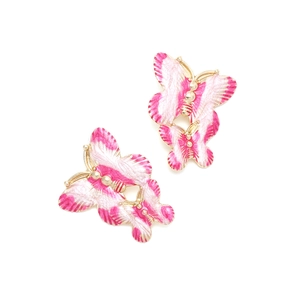 Detailed macro view of pink enamel butterfly earrings with gold-plated metal texture