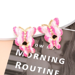 Detailed macro view of pink butterfly earrings with gold plating on a fashion magazine