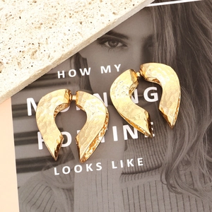 Textured gold-tone chunky C-shape heart earrings with hammered metal finish on magazine