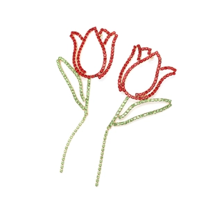 Détail macro de boucles d'oreilles tulipe avec strass rouges et verts sur alliage doré