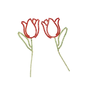 Détail de boucles d'oreilles tulipe rouge étincelantes avec des feuilles en cristal vert