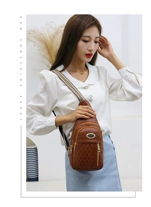 Brown quilted crossbody bag with golden zippers and striped canvas shoulder strap