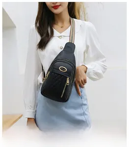 Detail of black quilted sling bag with striped strap and gold zipper on model