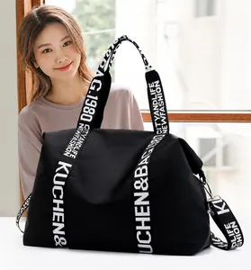 Detail of waterproof nylon tote bag showing white lettered straps and metal hooks