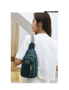 Detail view of dark green pebbled leather chest bag with embroidered quilting and canvas strap