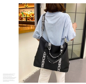 Detail of waterproof black nylon tote bag with stylish letter-printed straps on a model