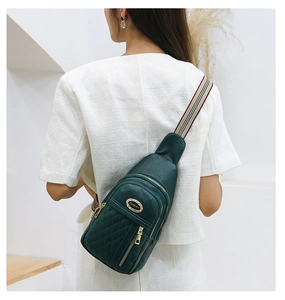 Detail of dark green leather crossbody bag featuring quilted patterns and striped strap