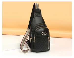 Detailed view of black quilted leather chest bag with striped strap and gold zippers
