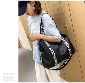 Side view of large black waterproof nylon tote bag with white letter print branding