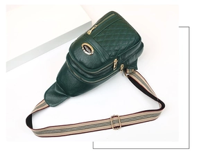 Detail of green quilted leather chest bag featuring multiple compartments and gold zippers