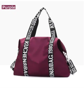 Detail of purple waterproof nylon travel bag with lettered webbing handles and metal hooks