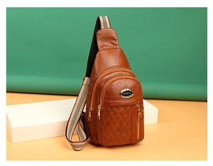 Detail of brown quilted faux leather chest bag with gold zippers and striped strap