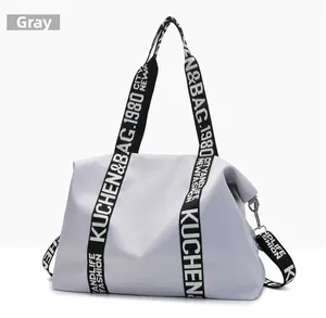 Close-up of durable grey nylon travel bag featuring contrast woven lettering straps