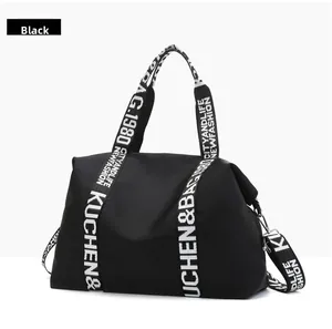 Detail of black waterproof nylon tote bag featuring lettered woven straps and side clips