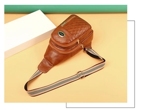 Detail of brown quilted leather chest bag featuring striped webbing strap and multi-zippers