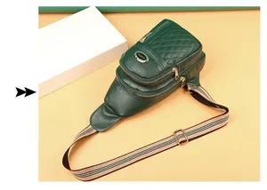 Detail of dark green quilted crossbody bag with striped strap and three gold zippers