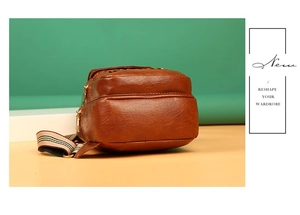 Close-up of brown quilted leather sling bag with textured finish and striped strap