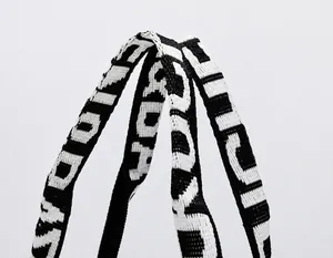 Macro shot of durable black and white woven handle with letter embroidery for tote bag