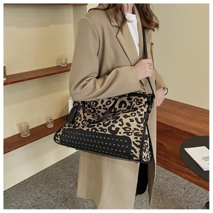 Detail of leopard print tote bag with black leather base, metal rivets and fringe tassel