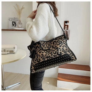 Detail of leopard print tote bag featuring silver studs and long black leather tassels