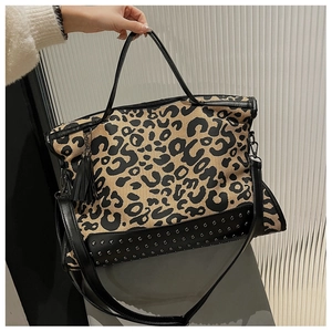 Detail of leopard print tote bag with dark metal rivets and black tassel pendant charm