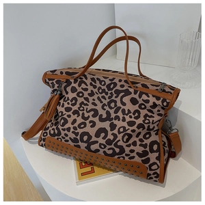 Detail view of leopard print tote bag with brown leather handles and metal rivets on bottom
