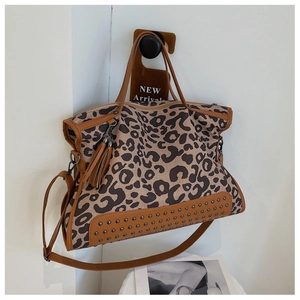 Close-up of leopard print tote bag with metallic studs, brown leather trim and tassels