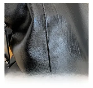 Close-up of black textured leather bag showcasing precise stitching and fine pebble grain