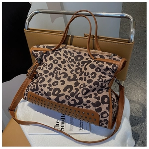 Detail of leopard print tote bag with brown leather trim and metallic bottom rivets