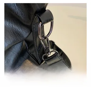 Detail of gunmetal spring hook on black lychee-grain leather tote bag with logo strap