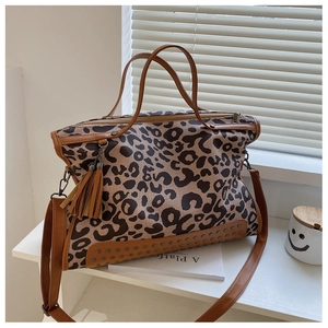 Close-up of leopard print tote bag featuring metallic rivets and stylish tassel detail