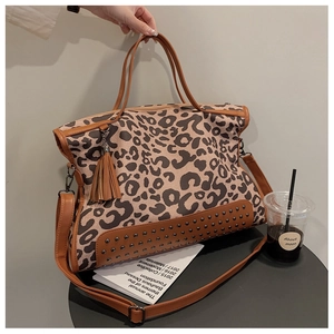 Detail view of leopard print tote bag featuring brown tassels and metal rivets on the bottom