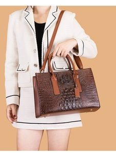 Détail du sac à main marron foncé effet crocodile avec pieds en métal et bandoulière
