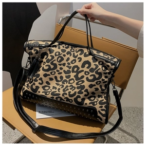 French leopard print tote bag with rivets and tassels shown in a modern interior setting