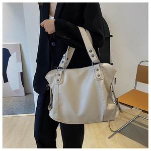 Detailed view of cream white tote bag with pebble texture and metallic rivet accents