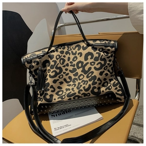 Detail of leopard print tote with metal studs and black leather trim on a chair