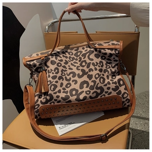 Macro detail of leopard print tote bag featuring bronze rivets and faux leather trim