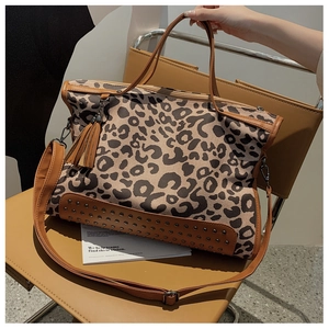 Close-up of leopard print tote bag featuring metallic rivet studs and leather tassel detail