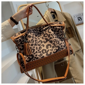 Detail of leopard print tote bag featuring vintage metal rivets and a tassel pendant