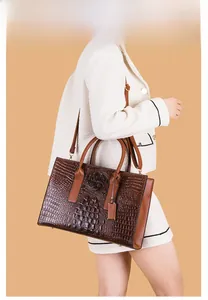 Sac à main marron foncé à motif crocodile porté en bandoulière par un mannequin