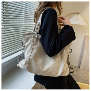 Detail of cream white tote bag with metal ring handle and soft textured PU leather
