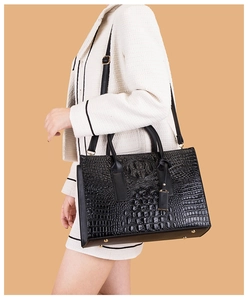 Détail du sac en cuir noir à motif crocodile avec rivets dorés et bandoulière réglable